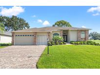 Charming single-story home features a well-manicured lawn, brick accents, and a spacious driveway leading to the garage at 7328 Blue Skies Dr, Spring Hill, FL 34606
