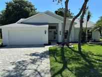Charming single-story home featuring a well-manicured lawn, brick driveway, and inviting front entrance at 8209 Golf Club Ct, Hudson, FL 34667