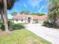 Charming single-story home with well-manicured lawn, mature palms, and a circular driveway at 9168 Southern Comfort Ct, Weeki Wachee, FL 34613