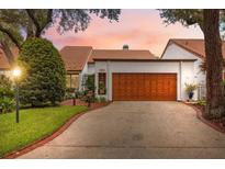 Charming home featuring a well-manicured lawn, warm-toned garage door, and welcoming curb appeal at 11505 Cerca Del Rio, Temple Terrace, FL 33617