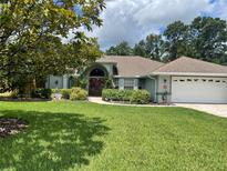 Charming single-story home featuring a manicured lawn, complemented by lush landscaping and a welcoming double door entry at 1231 Etta Ave, Spring Hill, FL 34609
