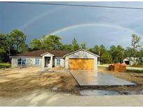 Charming one-story home with a double rainbow over the house and surrounding green trees at 14586 Mocking Wren Rd, Weeki Wachee, FL 34614