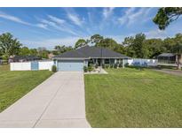 Charming one-story home featuring a well-manicured lawn, concrete driveway, and stylish light blue exterior at 2027 Fentress Ct, Spring Hill, FL 34609