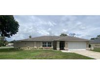 Charming single-story home with a well-manicured lawn and colorful flower beds at 3128 Montague Ave, Spring Hill, FL 34608