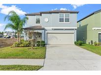 Charming two-story home featuring a two-car garage, well-maintained lawn, and complemented by a beautiful palm tree at 313 Argyll Dr, Spring Hill, FL 34609