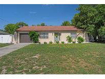 Charming single-story home featuring a well-manicured lawn, tidy landscaping, and an attached garage at 6347 Shadydale Ave, Spring Hill, FL 34609