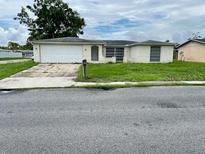 Modest one-story home featuring an attached garage and standard-sized front yard at 7714 Fox Hollow Dr, Port Richey, FL 34668