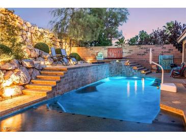 Inviting swimming pool with a rock waterfall and lighting at 11220 Romette Ct, Las Vegas, NV 89141