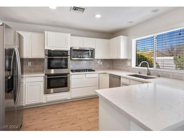 Modern kitchen with white cabinets, stainless steel appliances, and quartz countertops at 9028 Firebird Dr, Las Vegas, NV 89134