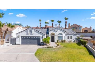 Single-story home with gray garage door and landscaped yard at 3652 Brian Ct, Laughlin, NV 89029