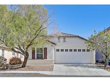 Single story home with white exterior, two car garage, and landscaping at 8524 Bighorn River St, Las Vegas, NV 89131