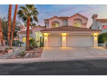 Two-story house with three-car garage, landscaping, and palm trees at 8125 Sunset Cove Dr, Las Vegas, NV 89128