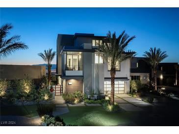 Night view of a modern luxury home with palm trees, showcasing its architectural design and landscaping at 619 Overlook Rim Dr, Henderson, NV 89012