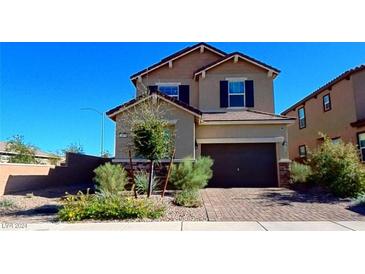 Two-story home with a tan exterior, landscaping, and a two-car garage at 417 Desert Cadence St, Henderson, NV 89011