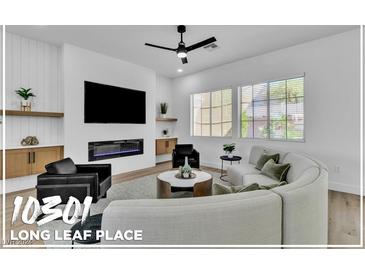 Modern living room featuring a curved sofa, fireplace, and built-in shelving at 10301 Long Leaf Pl, Las Vegas, NV 89134