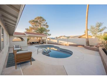 Inviting kidney-shaped pool with patio furniture and covered seating area at 6750 Laronda Ln, Las Vegas, NV 89156