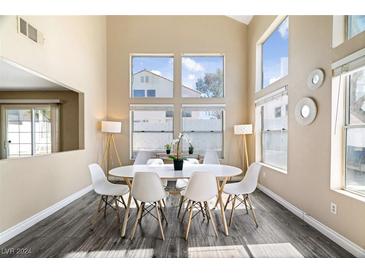 Bright dining room with large windows, hardwood floors, and a white oval table with chairs at 8213 Grassy Point Cir, Las Vegas, NV 89145