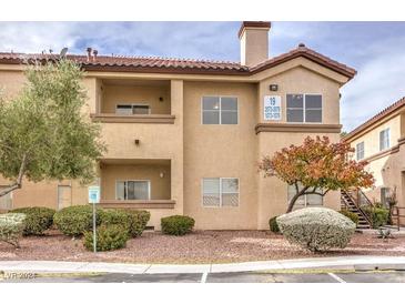 Two-story condo building with tan exterior, landscaping, and parking at 8501 W University Ave # 2076, Las Vegas, NV 89147