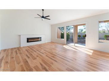 Bright living room with fireplace, wood floors, and sliding glass door at 9621 Blue Bell Dr, Las Vegas, NV 89134