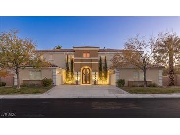 Two-story house with a beige facade, arched entryway, and landscaping at 8109 Dark Hollow Pl, Las Vegas, NV 89117