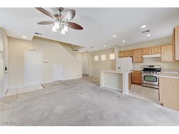 Open kitchen with island, stainless steel appliances, and light wood cabinets at 153 Sitka Spruce St, Henderson, NV 89015