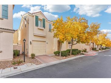 Tan two-story house with green shutters and a yellow tree in front at 7587 French Springs St, Las Vegas, NV 89139