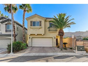 Tan two-story house with a white garage door and palm trees in the front at 10147 Dragons Meadow Ct, Las Vegas, NV 89148