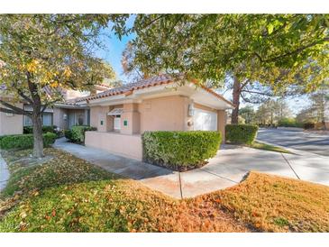 Tan stucco house with tile roof, lush landscaping, and a two-car garage at 5058 Crooked Stick Way, Las Vegas, NV 89113