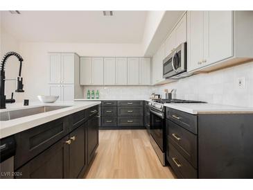 Modern kitchen with dark cabinetry, white countertops, and stainless steel appliances at 6436 Heatherton Ave, Las Vegas, NV 89110