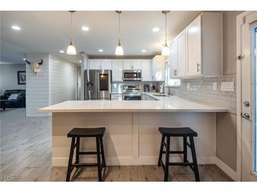 Modern kitchen with white cabinets, stainless steel appliances, and a breakfast bar at 1568 Seneca Ln, Las Vegas, NV 89169