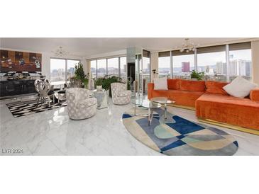 Bright living room with city views, orange sectional sofa, and marble floors at 3111 Bel Air Dr # 12G, Las Vegas, NV 89109