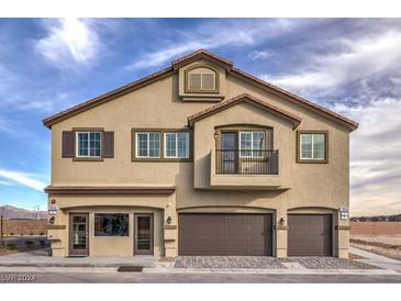 Tan two-story townhome with brown garage doors and balcony at 7945 Aurora Sky St # 641, North Las Vegas, NV 89084