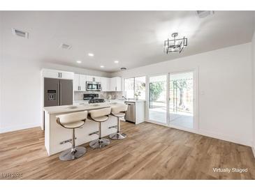 Modern white kitchen with island, stainless steel appliances, and light wood floors at 1000 Macfarlane St, Las Vegas, NV 89101