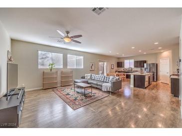 Open living room with hardwood floors, gray sectional sofa, and modern coffee table at 10421 Mount Washington Ave, Las Vegas, NV 89166