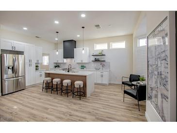 Modern kitchen with white cabinets, an island with seating, and stainless steel appliances at 10008 Hope Island Dr, Las Vegas, NV 89134