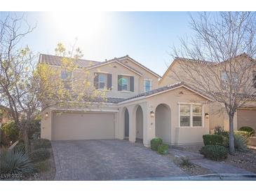 Two-story house with a beige exterior, brick driveway, and landscaping at 12241 Regal Springs Ct, Las Vegas, NV 89138