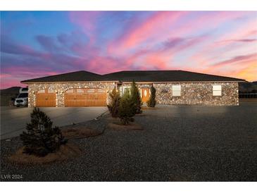 Stone exterior home with three-car garage at sunset at 2590 W Betty Ave, Pahrump, NV 89060