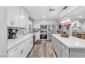 Modern kitchen features white cabinets, quartz countertops, and stainless steel appliances at 688 Moonlight Mesa Dr, Henderson, NV 89011