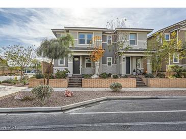 Two-story townhome with gray siding, brick accents, and a landscaped front yard at 754 N Water St, Henderson, NV 89015