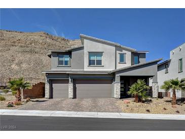 Modern three-car garage home with gray exterior and landscaping at 6481 Farness St, Las Vegas, NV 89135