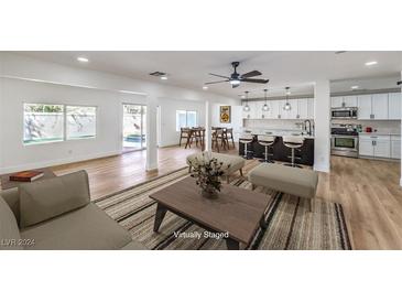 Bright, spacious living room with hardwood floors, modern furniture, and access to kitchen at 686 Ribbon Grass Ave, Las Vegas, NV 89183