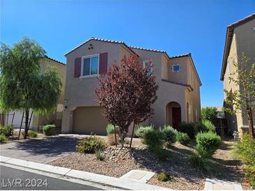 Two-story house with tan exterior, red door, and landscaping at 11467 Monte Isola St, Las Vegas, NV 89141