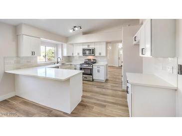 Modern kitchen featuring white cabinets, quartz countertops, and stainless steel appliances at 1941 Toscanini Way, North Las Vegas, NV 89032