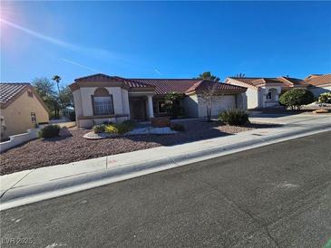 Single-story house with red tile roof, landscaping, and a large driveway at 8905 Sandspring Dr, Las Vegas, NV 89134