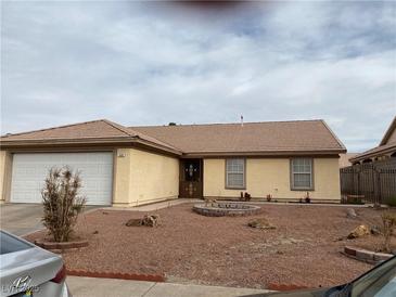 Beige house with brown tile roof, white garage door, and small front yard landscaping at 440 Pioneer St, Henderson, NV 89015