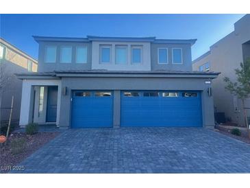 Two-story house with gray exterior, blue garage doors, and paved driveway at 629 Soaring Wings Ave, Las Vegas, NV 89183