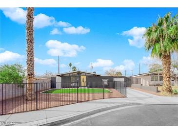 Cute mid-century modern home with a yellow door, artificial turf, and a black fence at 709 Osprey Cir, Las Vegas, NV 89107