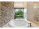 Bathroom with a large soaking tub and a window overlooking trees at 12 Canoa Hills Dr, Henderson, NV 89052