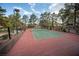 Well-maintained tennis court with red surface and green net, surrounded by trees and landscaping at 2841 Glendevon Cir, Henderson, NV 89014