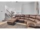 Spacious living room with a brown sectional sofa and a staircase at 10664 Sariah Skye Ave, Las Vegas, NV 89166